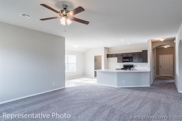 8508 E Queens St, Broken Arrow, OK 74014 - unfurnished living room with arched walkways, light carpet, baseboards, a ceiling fan, and lofted ceiling