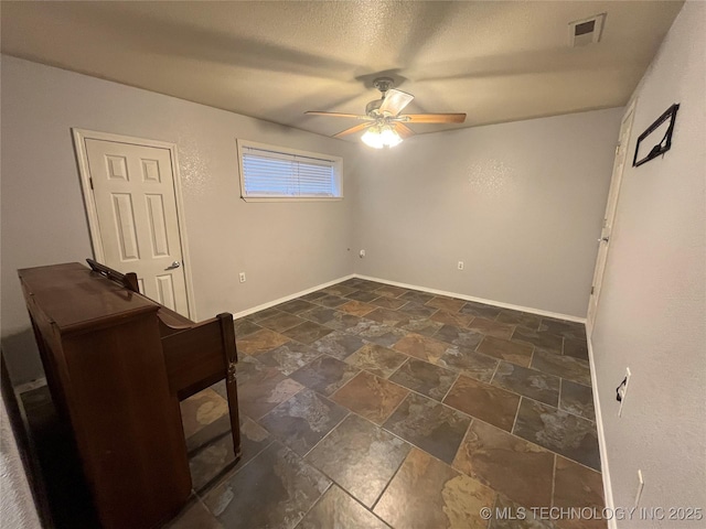114227 S 4172nd Rd, Checotah, OK 74426 - unfurnished room featuring a ceiling fan, stone tile flooring, baseboards, and a textured ceiling