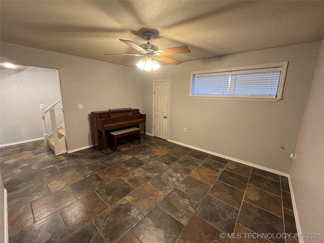 114227 S 4172nd Rd, Checotah, OK 74426 - empty room with a ceiling fan, stone tile floors, baseboards, a textured ceiling, and stairway