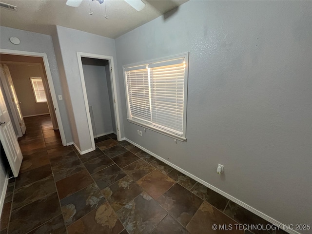 114227 S 4172nd Rd, Checotah, OK 74426 - unfurnished bedroom with baseboards, dark stone finish floors, a closet, and ceiling fan