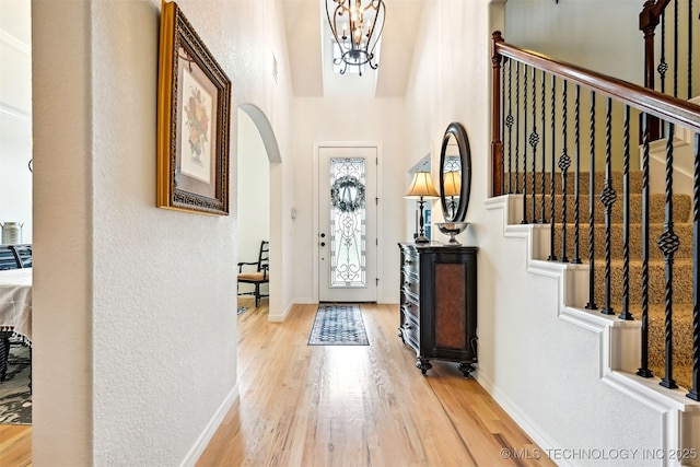 16425 E 49th St, Tulsa, OK 74134 - foyer with arched walkways, light wood-style flooring, a chandelier, a towering ceiling, and a textured wall