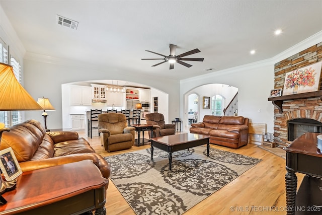 16425 E 49th St, Tulsa, OK 74134 - living area featuring arched walkways, a ceiling fan, stairway, a fireplace, and ornamental molding