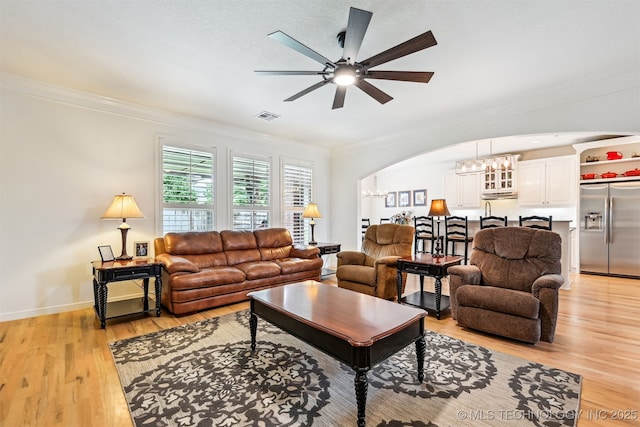 16425 E 49th St, Tulsa, OK 74134 - living room with ornamental molding, ceiling fan, light wood-type flooring, arched walkways, and a chandelier