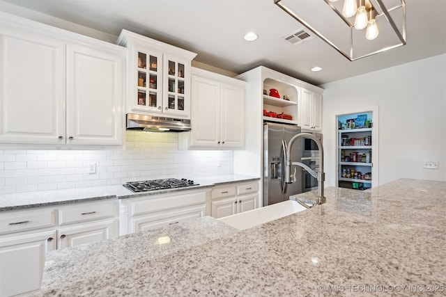16425 E 49th St, Tulsa, OK 74134 - kitchen featuring under cabinet range hood, stainless steel appliances, white cabinetry, light stone countertops, and tasteful backsplash