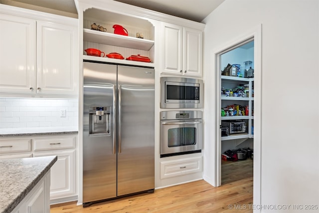 16425 E 49th St, Tulsa, OK 74134 - kitchen with appliances with stainless steel finishes, light wood-type flooring, white cabinetry, tasteful backsplash, and light stone counters