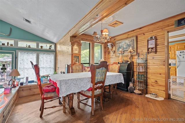 6721 Swayback, Sulphur, OK 73086 - dining space featuring a chandelier, wooden walls, vaulted ceiling, hardwood / wood-style flooring, and a textured ceiling