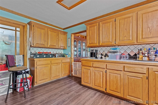 6721 Swayback, Sulphur, OK 73086 - kitchen featuring backsplash, light wood-style flooring, light countertops, ornamental molding, and brown cabinetry