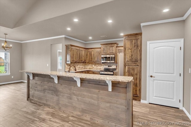 97 Paytons Pl, Durant, OK 74701 - kitchen with stainless steel appliances, a kitchen breakfast bar, a sink, light stone countertops, and ornamental molding