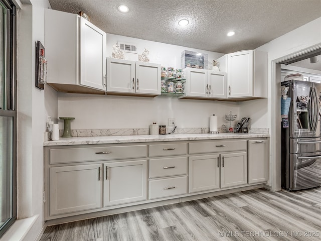 25206 E 64th St, Broken Arrow, OK 74012 - kitchen with stainless steel refrigerator with ice dispenser, a textured ceiling, light wood-type flooring, recessed lighting, and light stone counters