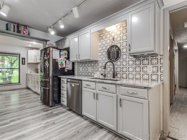 25206 E 64th St, Broken Arrow, OK 74012 - kitchen with appliances with stainless steel finishes, a sink, light wood finished floors, tasteful backsplash, and a textured ceiling