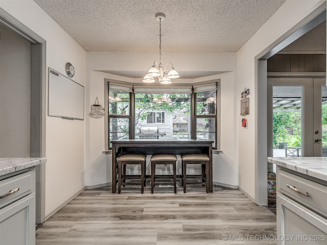 25206 E 64th St, Broken Arrow, OK 74012 - dining space with a chandelier, a textured ceiling, plenty of natural light, and light wood finished floors