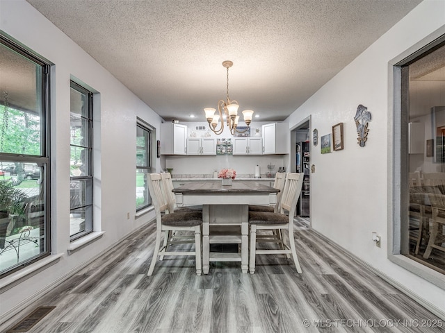 25206 E 64th St, Broken Arrow, OK 74012 - dining room with a chandelier, light wood-style floors, and a textured ceiling