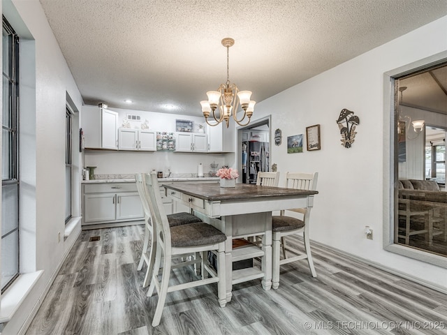 25206 E 64th St, Broken Arrow, OK 74012 - dining room featuring light wood-style floors, a chandelier, and a textured ceiling