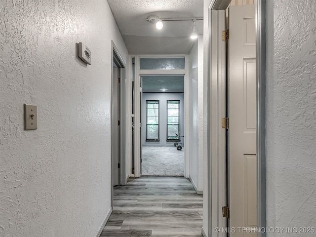 25206 E 64th St, Broken Arrow, OK 74012 - hallway featuring a textured wall, a textured ceiling, wood finished floors, baseboards, and track lighting