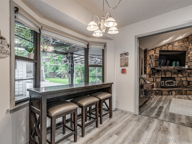 25206 E 64th St, Broken Arrow, OK 74012 - dining area featuring healthy amount of natural light, a textured ceiling, light wood-style floors, a chandelier, and lofted ceiling