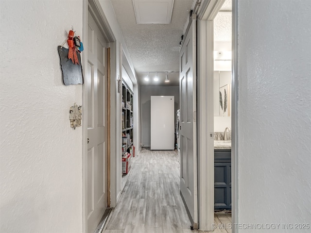 25206 E 64th St, Broken Arrow, OK 74012 - hall with rail lighting, a textured ceiling, a textured wall, a sink, and light wood-style floors