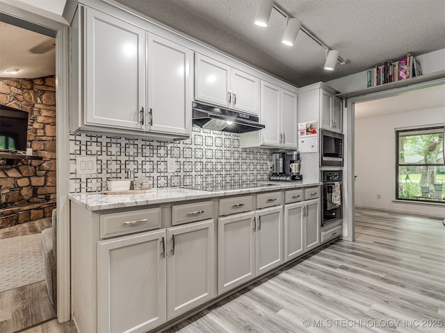 25206 E 64th St, Broken Arrow, OK 74012 - kitchen featuring black appliances, under cabinet range hood, light wood-style floors, decorative backsplash, and a textured ceiling
