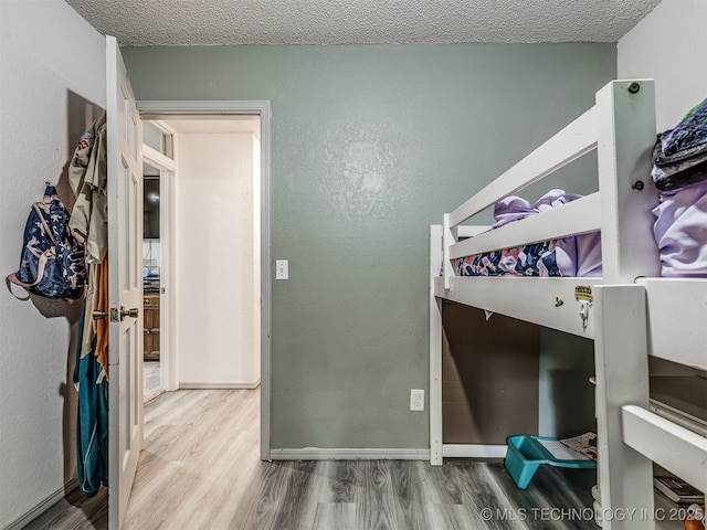 25206 E 64th St, Broken Arrow, OK 74012 - unfurnished bedroom with wood finished floors, baseboards, a textured ceiling, and a textured wall