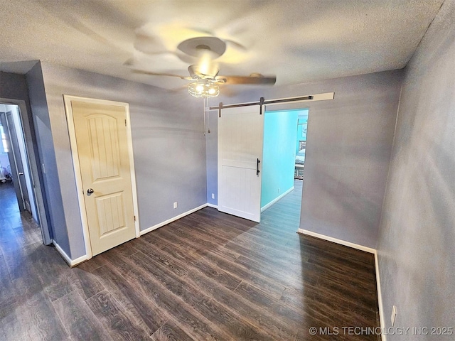 1306 E Shawnee St, Tahlequah, OK 74464 - empty room featuring a barn door, a ceiling fan, dark wood finished floors, and a textured ceiling