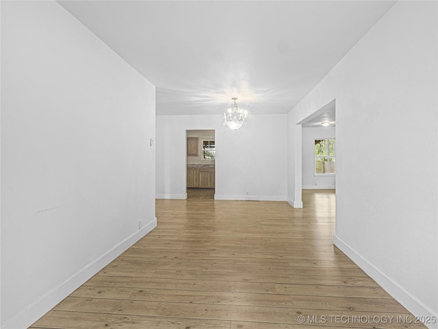 148 W 4th, Atoka, OK 74525 - unfurnished room with a chandelier, light wood-style flooring, and baseboards