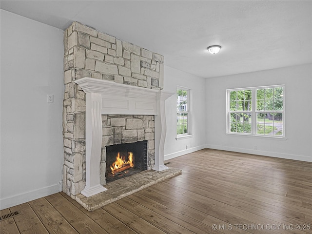 148 W 4th, Atoka, OK 74525 - unfurnished living room featuring a fireplace, hardwood / wood-style floors, and baseboards