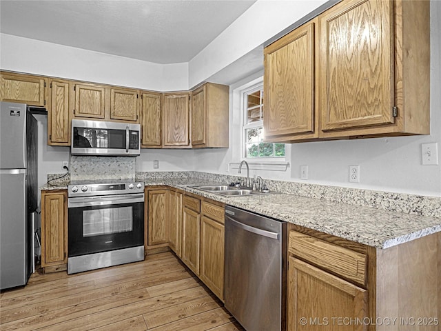 148 W 4th, Atoka, OK 74525 - kitchen with appliances with stainless steel finishes, a sink, light wood-style floors, and light stone counters