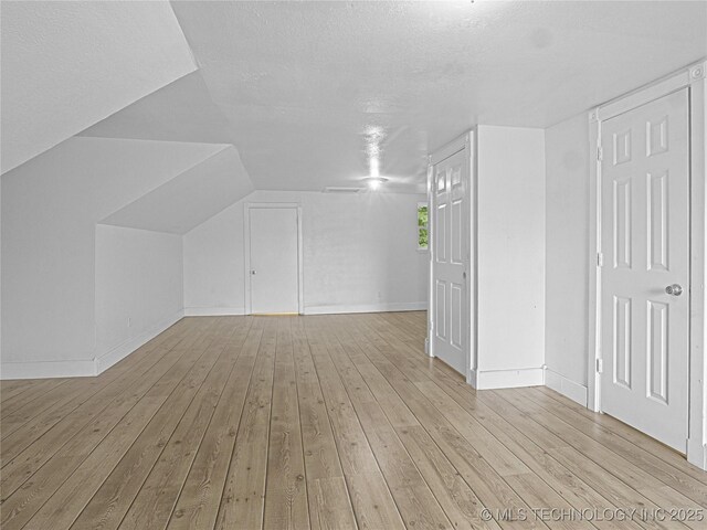148 W 4th, Atoka, OK 74525 - additional living space featuring light wood-style floors, baseboards, a textured ceiling, and lofted ceiling