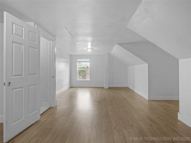 148 W 4th, Atoka, OK 74525 - bonus room featuring a textured ceiling, baseboards, hardwood / wood-style floors, and vaulted ceiling