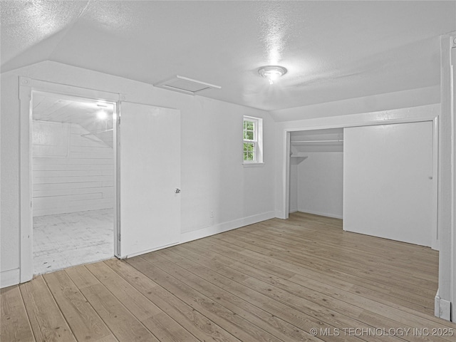 148 W 4th, Atoka, OK 74525 - unfurnished bedroom with a textured ceiling, lofted ceiling, hardwood / wood-style flooring, connected bathroom, and a closet
