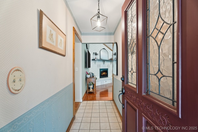 foyer entrance with a brick fireplace and light tile patterned flooring