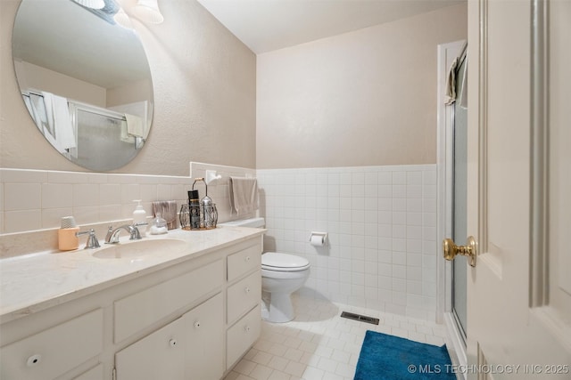 107 W 12th St Unit 107, Bartlesville, OK 74003 - full bathroom with tile walls, vanity, tile patterned flooring, a shower with door, and toilet
