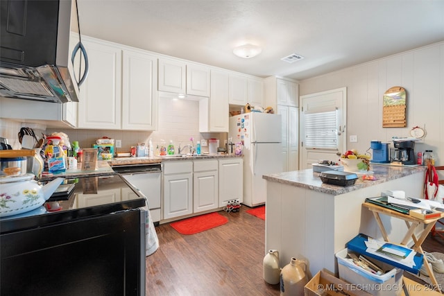 107 W 12th St Unit 107, Bartlesville, OK 74003 - kitchen with white appliances, wood finished floors, white cabinets, a peninsula, and decorative backsplash