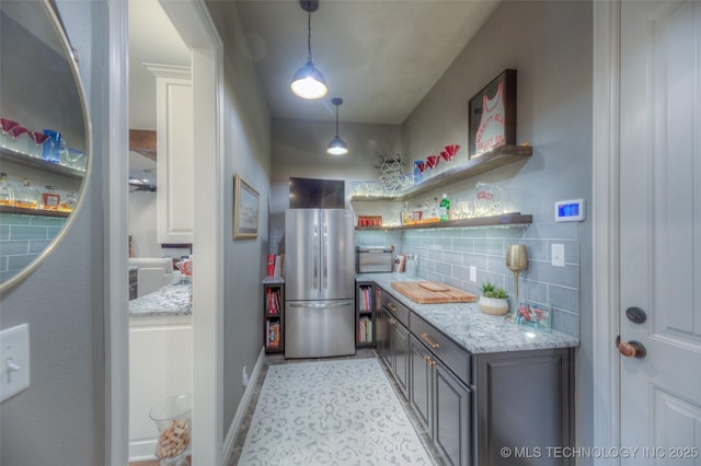 6623 E 134th Pl S, Bixby, OK 74008 - kitchen featuring freestanding refrigerator, backsplash, decorative light fixtures, light stone countertops, and baseboards