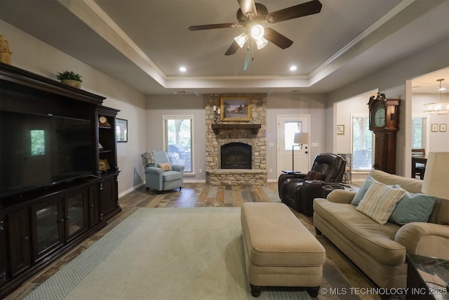 17061 S Creekwood Trl, Claremore, OK 74017 - living room featuring a raised ceiling, wood finished floors, a stone fireplace, a ceiling fan, and ornamental molding