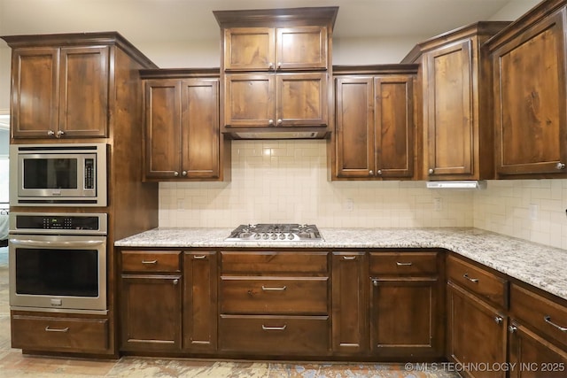 17061 S Creekwood Trl, Claremore, OK 74017 - kitchen with appliances with stainless steel finishes, decorative backsplash, and light stone countertops