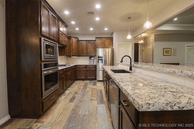 17061 S Creekwood Trl, Claremore, OK 74017 - kitchen with appliances with stainless steel finishes, a sink, dark brown cabinetry, light stone countertops, and recessed lighting