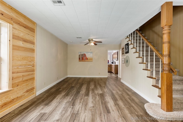 616 S Schlegel, Cushing, OK 74023 - unfurnished living room featuring wood finished floors, ceiling fan, stairs, wooden walls, and baseboards