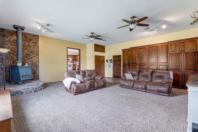 616 S Schlegel, Cushing, OK 74023 - carpeted living room featuring rail lighting, ceiling fan, a wood stove, and a textured ceiling