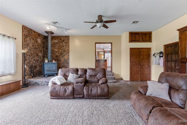 616 S Schlegel, Cushing, OK 74023 - living room featuring carpet floors, a wood stove, a ceiling fan, and a textured ceiling