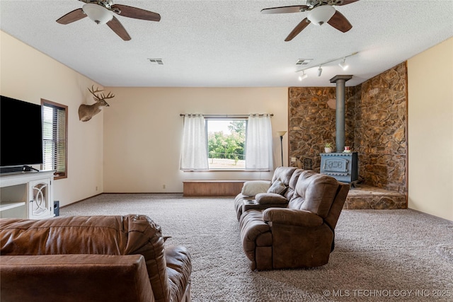 616 S Schlegel, Cushing, OK 74023 - carpeted living room with a ceiling fan, a wood stove, plenty of natural light, and a textured ceiling