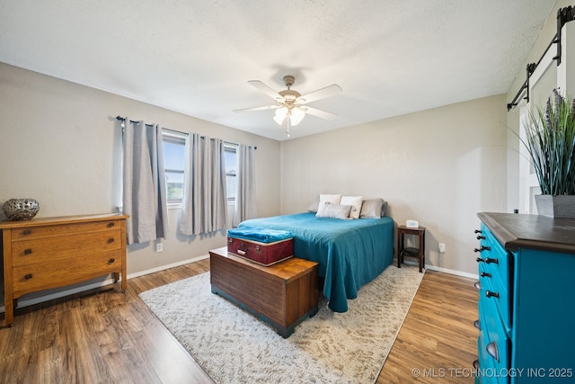 12350 E 138th St S, Broken Arrow, OK 74011 - bedroom with wood finished floors, baseboards, a textured ceiling, ceiling fan, and a barn door