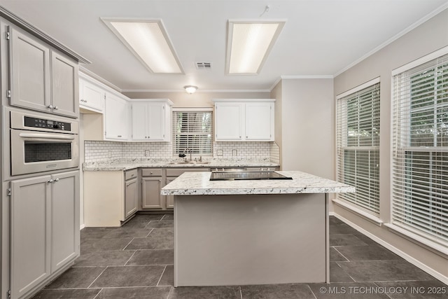 4908 S Redbud Ave, Broken Arrow, OK 74011 - kitchen featuring stainless steel oven, ornamental molding, tasteful backsplash, a kitchen island, and a sink