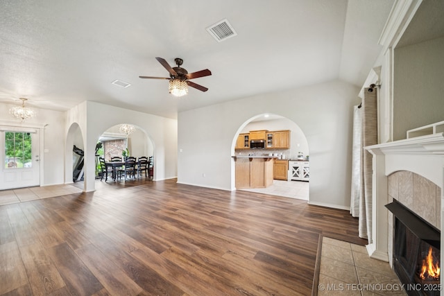 109 W 133rd Pl, Skiatook, OK 74070 - unfurnished living room with arched walkways, a tile fireplace, wood finished floors, and a chandelier