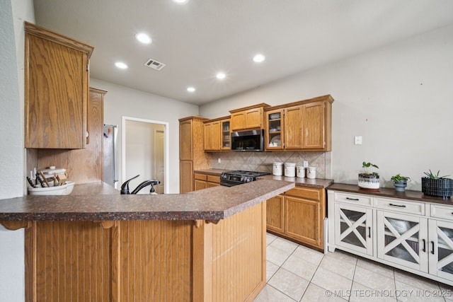 109 W 133rd Pl, Skiatook, OK 74070 - kitchen with appliances with stainless steel finishes, a peninsula, backsplash, light tile patterned floors, and glass insert cabinets