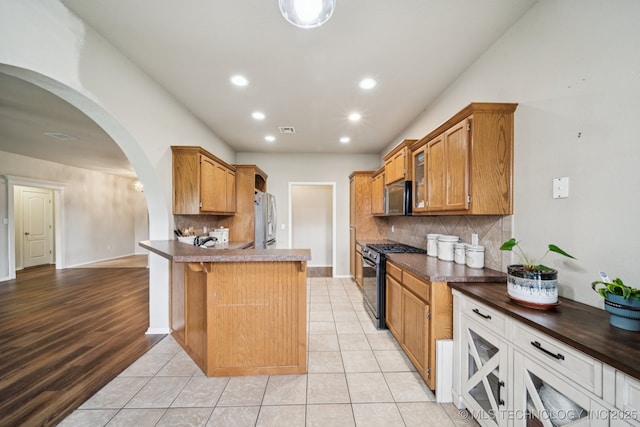 109 W 133rd Pl, Skiatook, OK 74070 - kitchen featuring stainless steel appliances, arched walkways, dark countertops, decorative backsplash, and recessed lighting