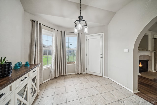109 W 133rd Pl, Skiatook, OK 74070 - foyer entrance with arched walkways, a chandelier, baseboards, a lit fireplace, and lofted ceiling