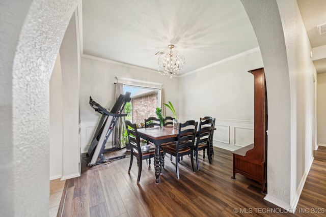 109 W 133rd Pl, Skiatook, OK 74070 - dining space featuring wood finished floors, arched walkways, a chandelier, a wainscoted wall, and crown molding