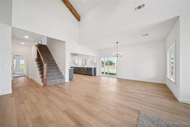 2410 W Charleston St, Broken Arrow, OK 74011 - unfurnished living room with a chandelier, stairs, light wood finished floors, beam ceiling, and baseboards