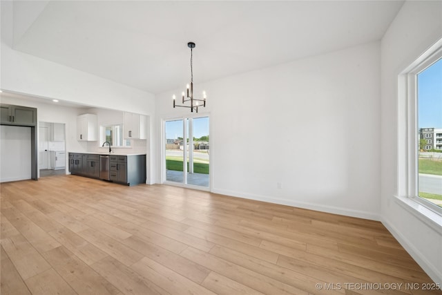2410 W Charleston St, Broken Arrow, OK 74011 - unfurnished living room featuring a chandelier, light wood-style flooring, and baseboards