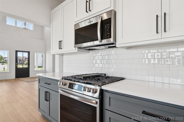 2410 W Charleston St, Broken Arrow, OK 74011 - kitchen with stainless steel appliances, gray cabinets, light countertops, decorative backsplash, and a chandelier